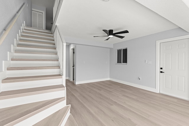 staircase featuring ceiling fan and light wood-type flooring