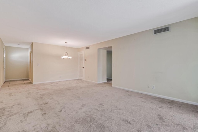 carpeted empty room featuring a notable chandelier