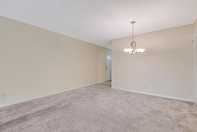 spare room featuring carpet floors and a notable chandelier