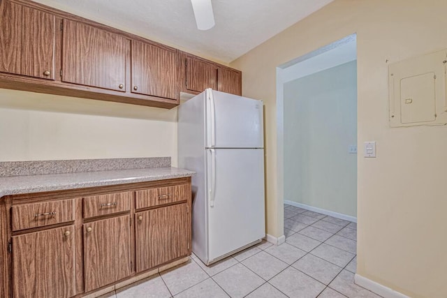 kitchen with electric panel, ceiling fan, white fridge, and light tile patterned floors