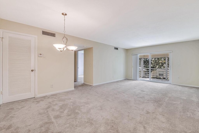 carpeted empty room featuring a notable chandelier