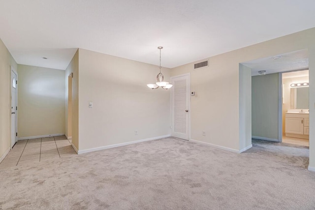 empty room featuring a chandelier and light colored carpet