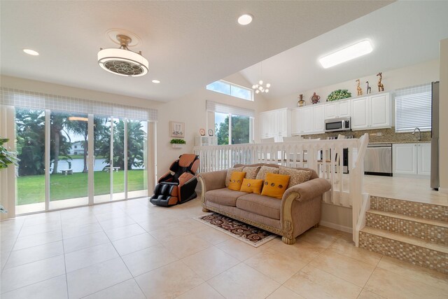 tiled living room with sink, lofted ceiling, and a chandelier