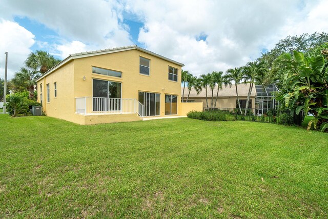 back of property featuring glass enclosure, a yard, and central air condition unit