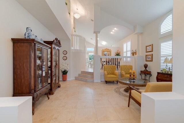 sitting room featuring a towering ceiling, decorative columns, and light tile floors