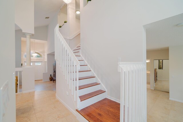 staircase featuring ornate columns and light tile floors