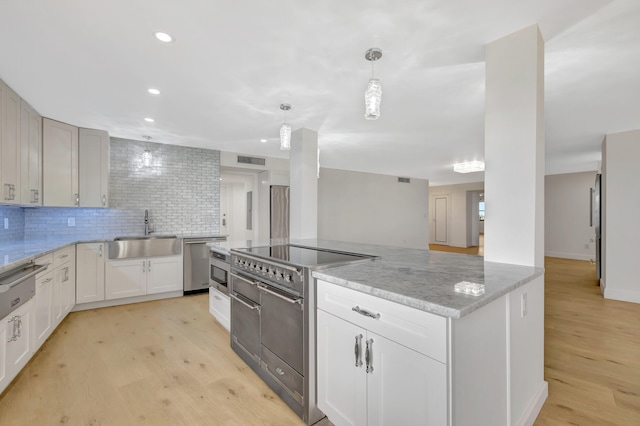 kitchen featuring tasteful backsplash, light stone counters, light hardwood / wood-style floors, hanging light fixtures, and sink