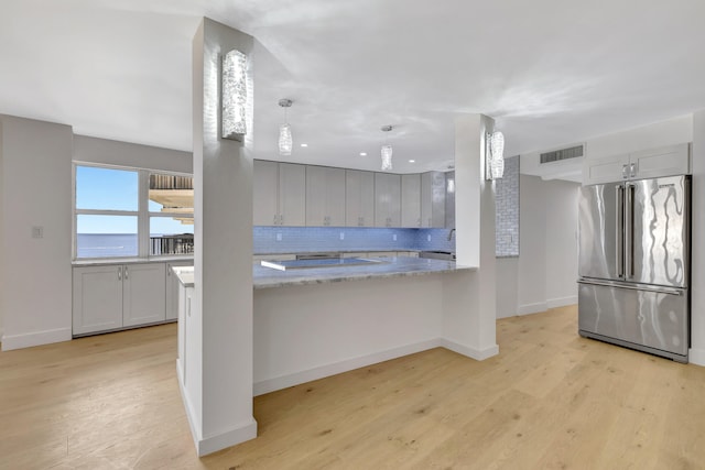 kitchen with light hardwood / wood-style flooring, tasteful backsplash, kitchen peninsula, high end refrigerator, and gray cabinetry