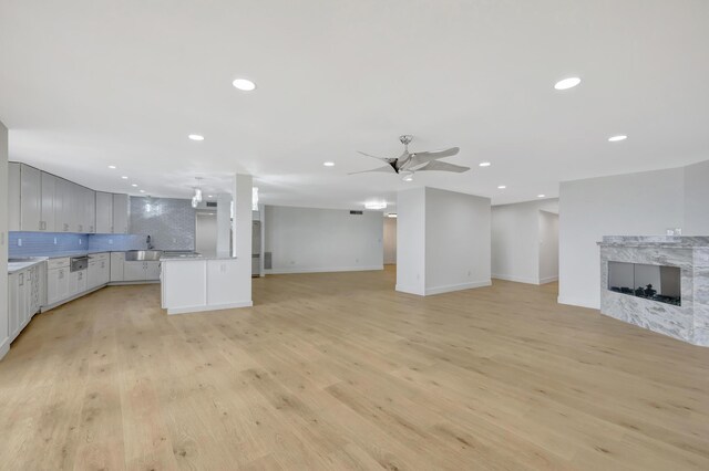 unfurnished living room with light hardwood / wood-style flooring, sink, and ceiling fan