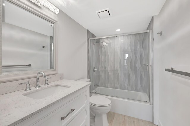 full bathroom featuring vanity, bath / shower combo with glass door, and toilet