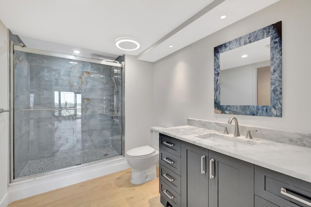 bathroom with vanity, a shower with door, hardwood / wood-style floors, and toilet