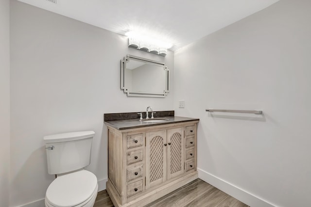 bathroom featuring wood-type flooring, toilet, and vanity