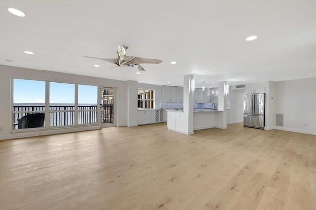 unfurnished living room with sink, light wood-type flooring, and ceiling fan