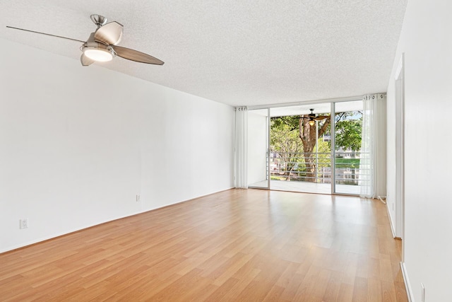 unfurnished room featuring expansive windows, light hardwood / wood-style floors, and a textured ceiling