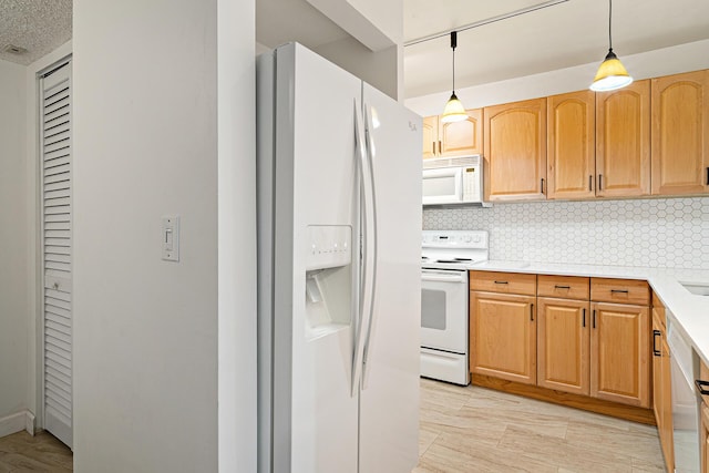 kitchen featuring backsplash, light hardwood / wood-style flooring, hanging light fixtures, and white appliances