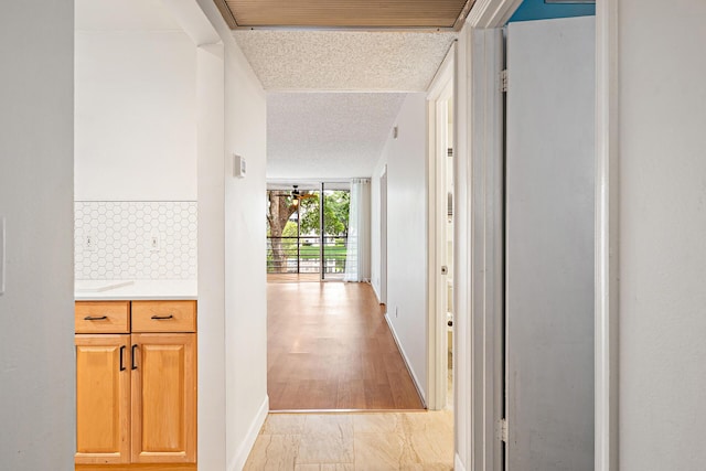 hallway with light hardwood / wood-style floors, a wall of windows, and a textured ceiling