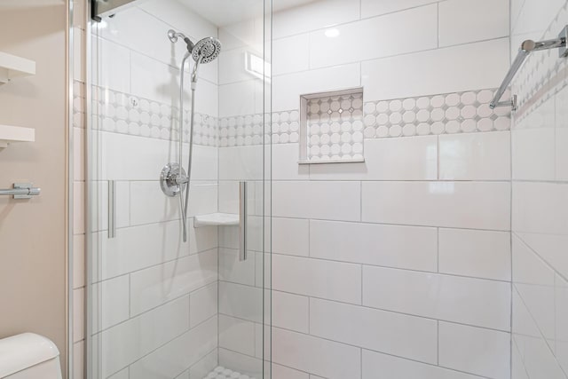 bathroom featuring toilet and a shower with shower door