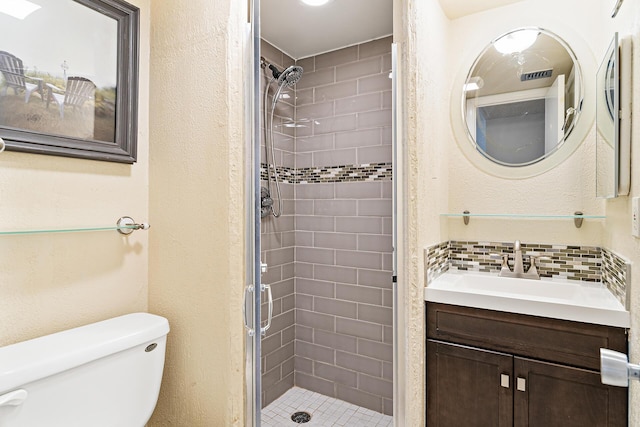 bathroom featuring vanity, backsplash, toilet, and a shower with shower door