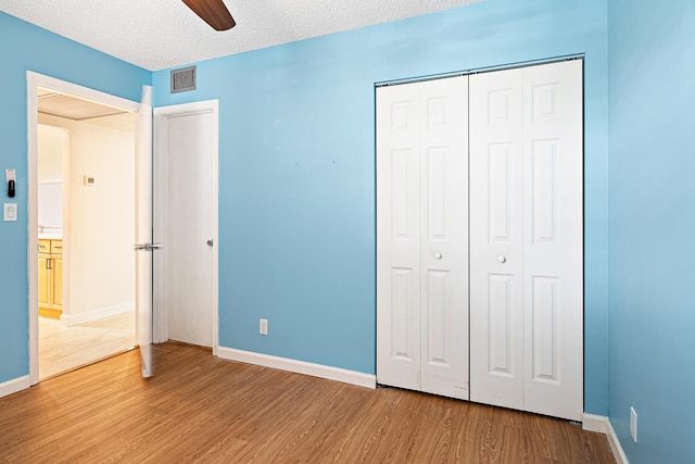 unfurnished bedroom featuring ceiling fan, light wood-type flooring, a textured ceiling, and a closet