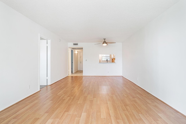 unfurnished room with ceiling fan, light wood-type flooring, and a textured ceiling