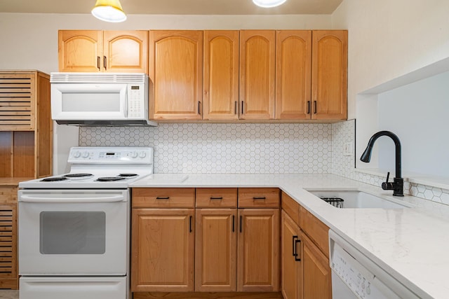 kitchen featuring white appliances, backsplash, light stone counters, and sink