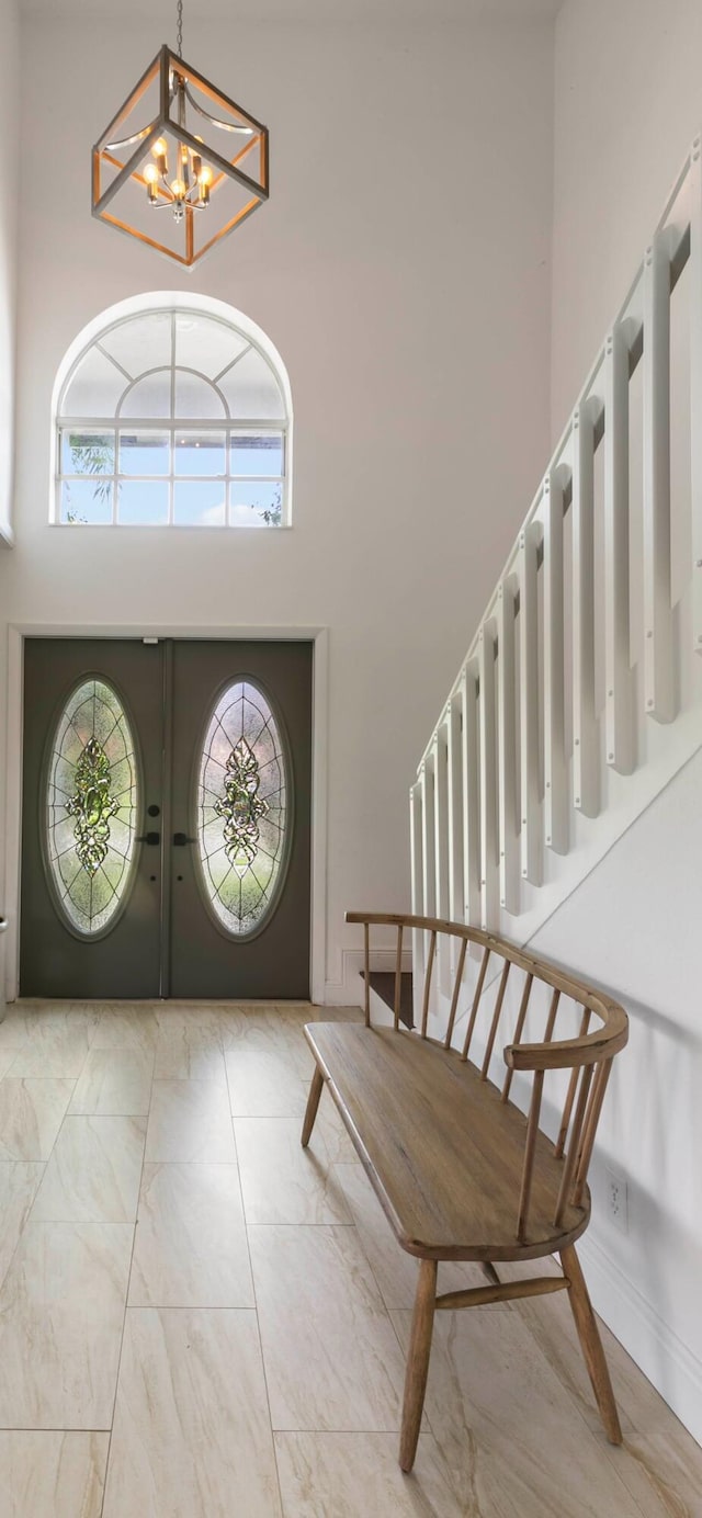 entrance foyer with a towering ceiling, plenty of natural light, stairway, and a notable chandelier