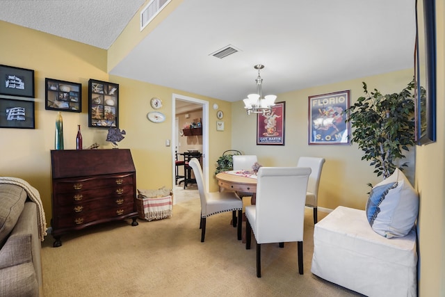 dining space with light colored carpet, a textured ceiling, and a notable chandelier