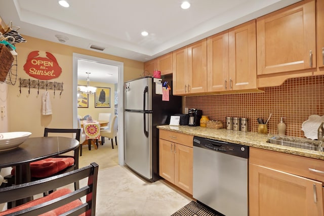 kitchen with a chandelier, light brown cabinetry, stainless steel appliances, and light stone countertops