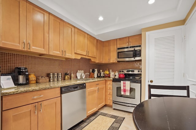 kitchen featuring light stone countertops, sink, stainless steel appliances, tasteful backsplash, and light tile patterned flooring