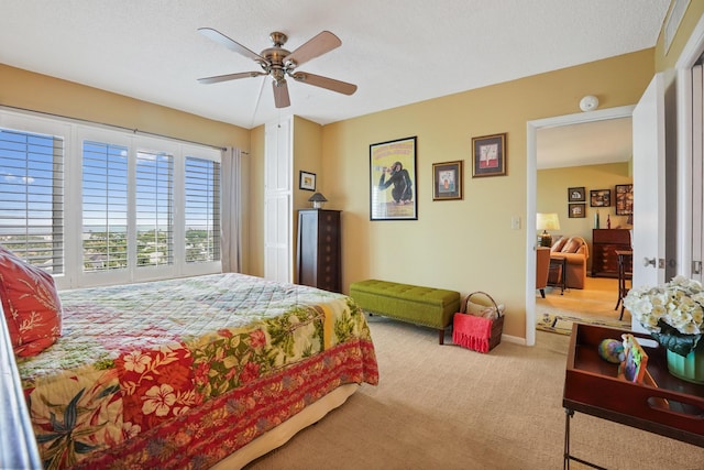 bedroom featuring a textured ceiling, light colored carpet, and ceiling fan