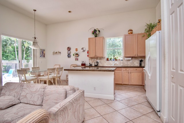 kitchen featuring white refrigerator with ice dispenser, pendant lighting, light brown cabinets, and light tile patterned floors