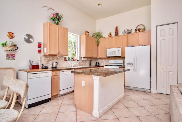 kitchen featuring a center island, light brown cabinets, white appliances, decorative backsplash, and light tile patterned flooring