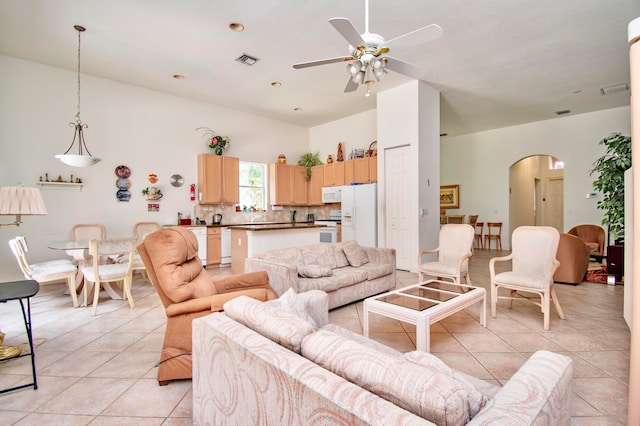 tiled living room featuring ceiling fan and a high ceiling