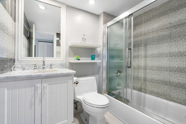 full bathroom featuring vanity, combined bath / shower with glass door, and toilet