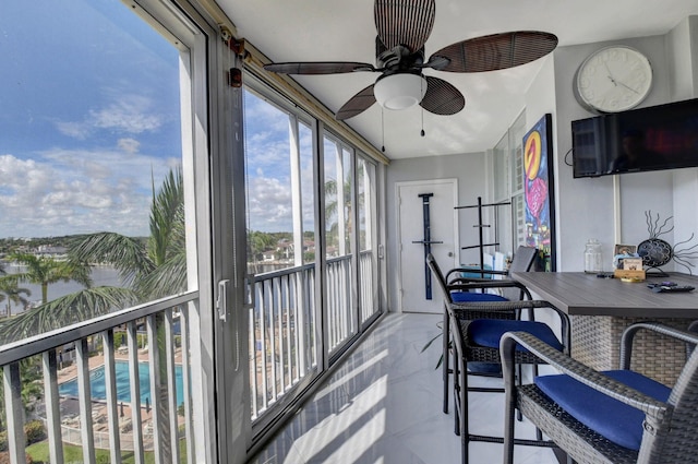 sunroom featuring plenty of natural light, ceiling fan, and a water view