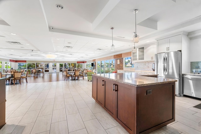 kitchen featuring stone counters, appliances with stainless steel finishes, a healthy amount of sunlight, and white cabinets