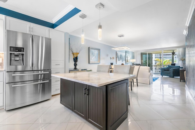 kitchen with a center island, stainless steel fridge with ice dispenser, pendant lighting, light stone countertops, and white cabinets