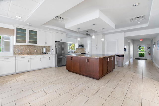 kitchen with a center island, stainless steel appliances, a raised ceiling, and white cabinets