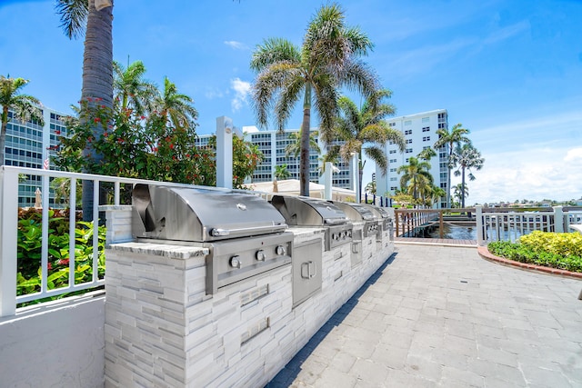 view of patio featuring grilling area, a water view, and exterior kitchen