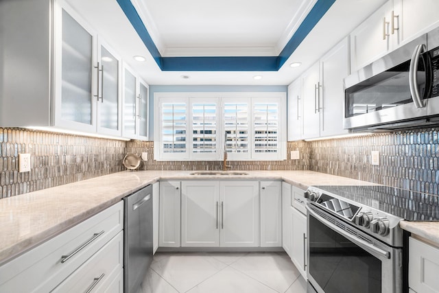 kitchen with light tile patterned flooring, white cabinetry, sink, stainless steel appliances, and crown molding