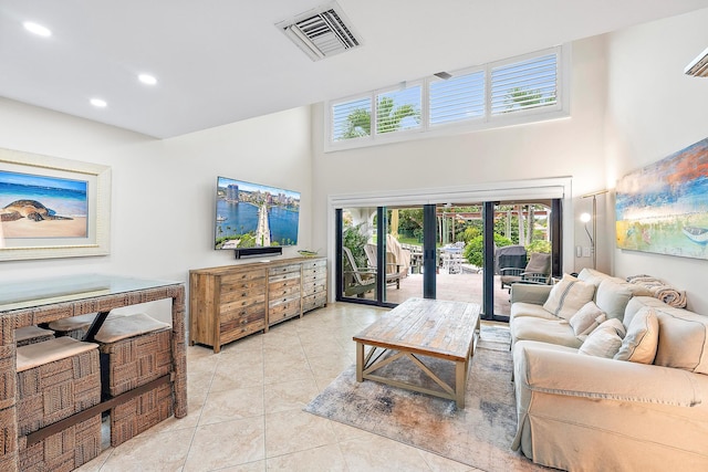 living room with french doors, light tile patterned floors, and a towering ceiling