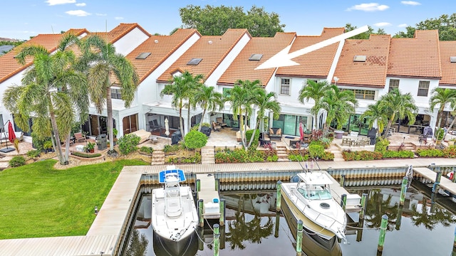 view of dock featuring a patio, a water view, and a yard