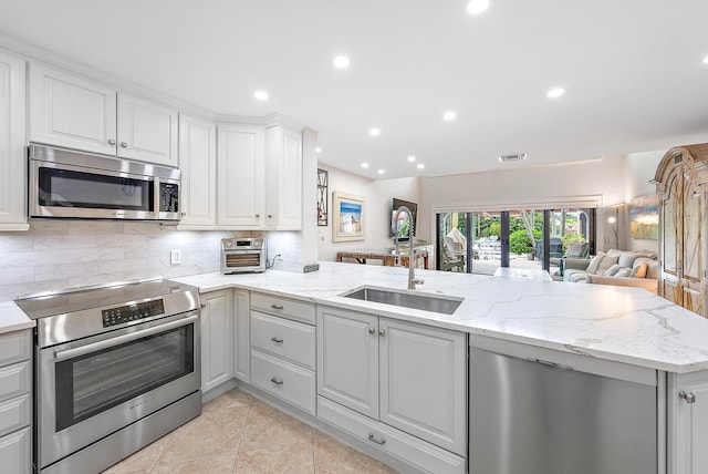 kitchen featuring light tile patterned flooring, range, sink, kitchen peninsula, and backsplash