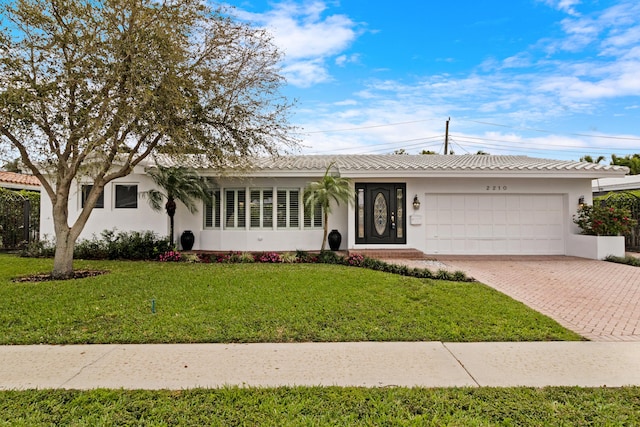 single story home with a garage, decorative driveway, a front lawn, and stucco siding