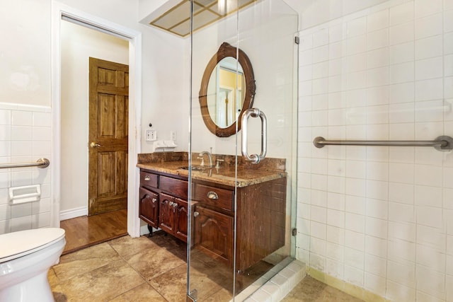 bathroom featuring a shower with door, toilet, tile walls, and vanity