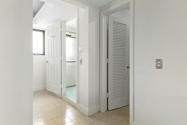 hallway with light tile patterned floors and baseboards