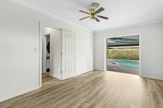 empty room featuring a ceiling fan, crown molding, baseboards, and wood finished floors