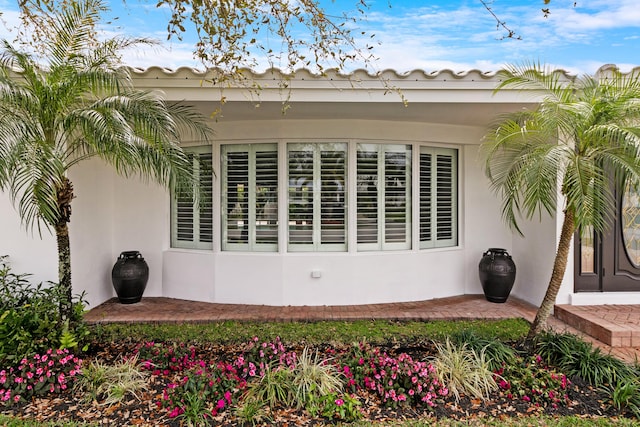 view of side of property with a tile roof and stucco siding