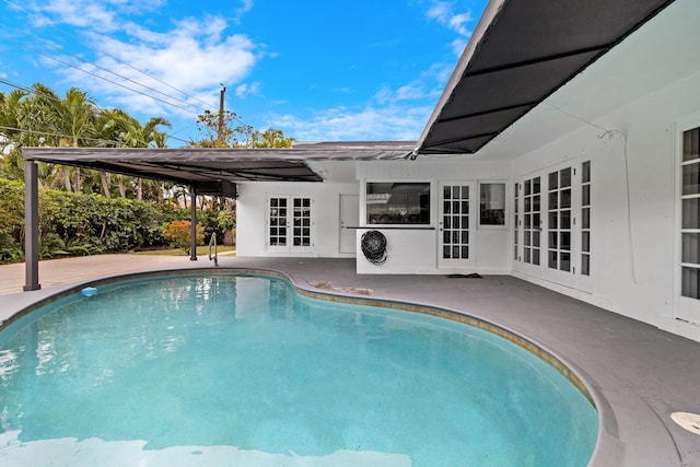 outdoor pool with french doors and a patio area