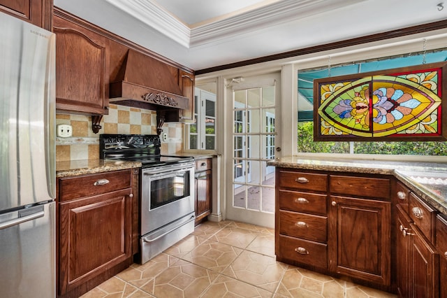 kitchen featuring crown molding, premium range hood, light stone countertops, decorative backsplash, and stainless steel appliances